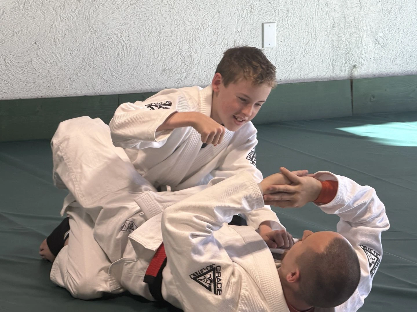 Young student practicing Brazilian Jiu-Jitsu with an instructor
