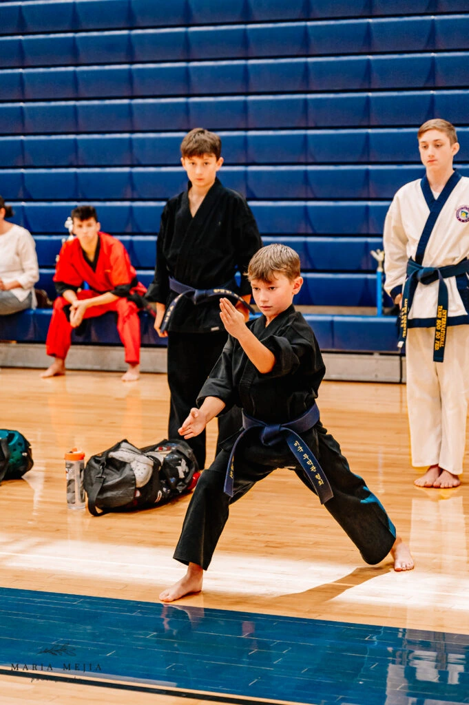 Student demonstrating martial arts form in a gymnasium