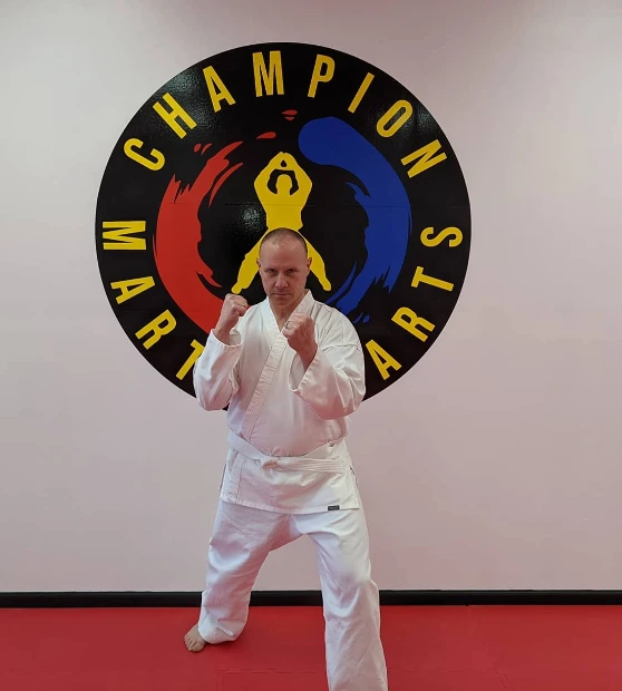 Master instructor posing in front of the Champion Martial Arts logo