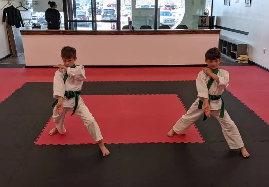 Two students practicing martial arts forms on the mat