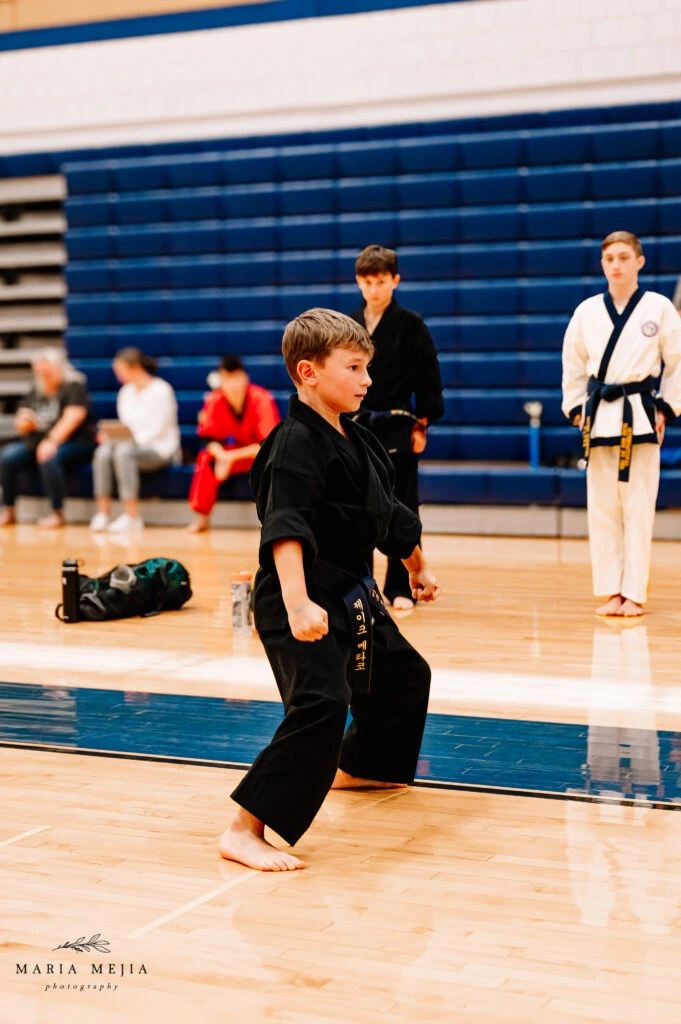 Student performing a martial arts form in a gymnasium