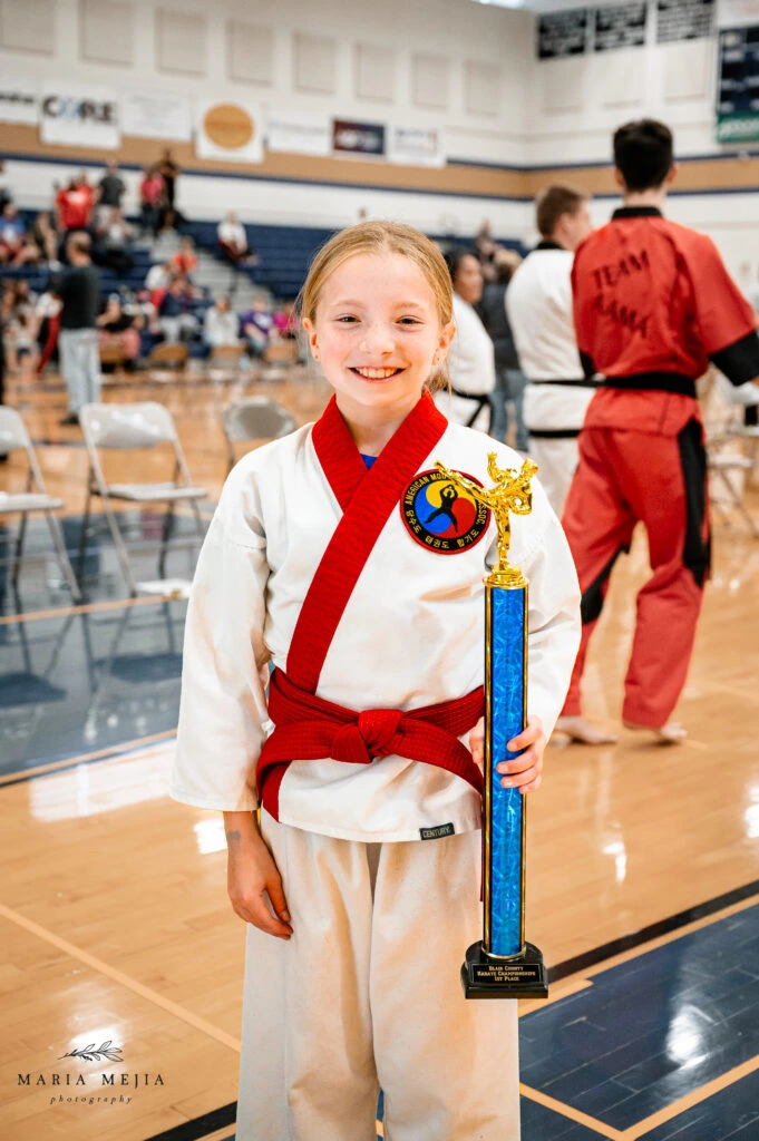 Young martial arts student holding a tournament trophy at Champion Martial Arts