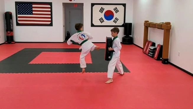 Two students practicing kicks in the Champion Martial Arts training room