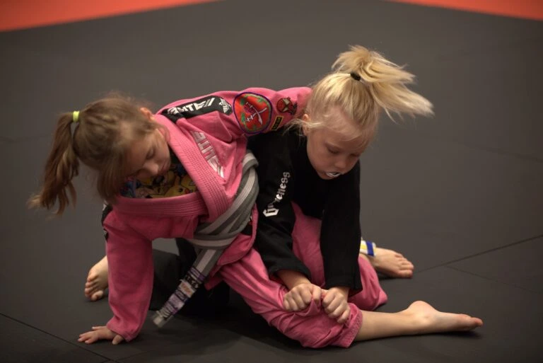 Two young students practicing Brazilian Jiu Jitsu on the mat
