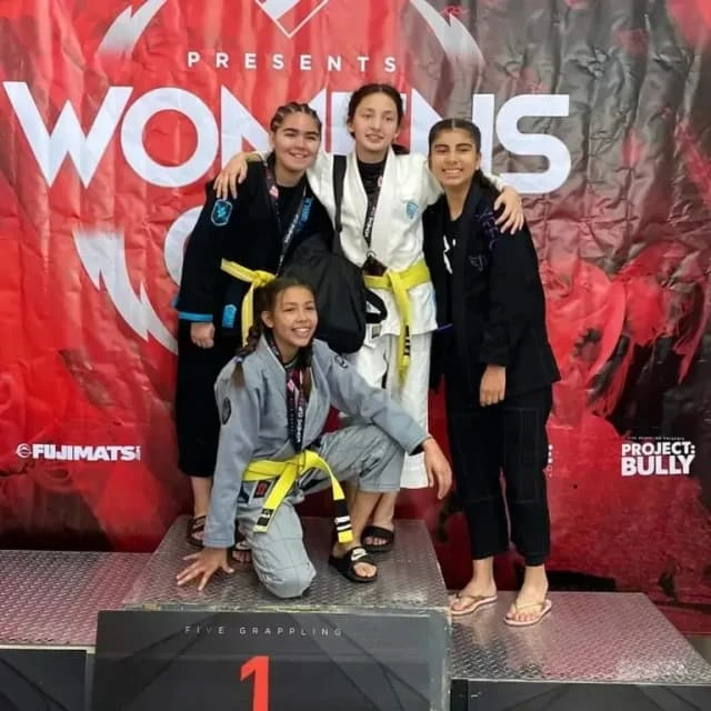 Students posing with medals at a jiu-jitsu event