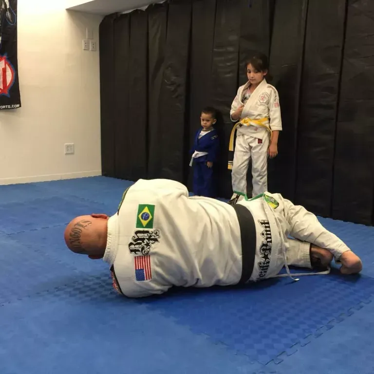 Kids training at Roll Dogs Jiu Jitsu while an instructor demonstrates on the mat